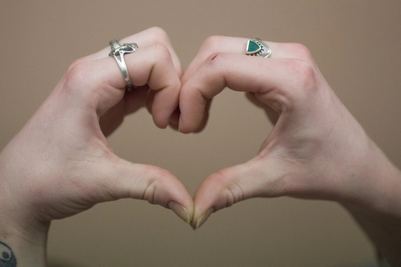 Close-up of two hands with rings forming a heart shape
