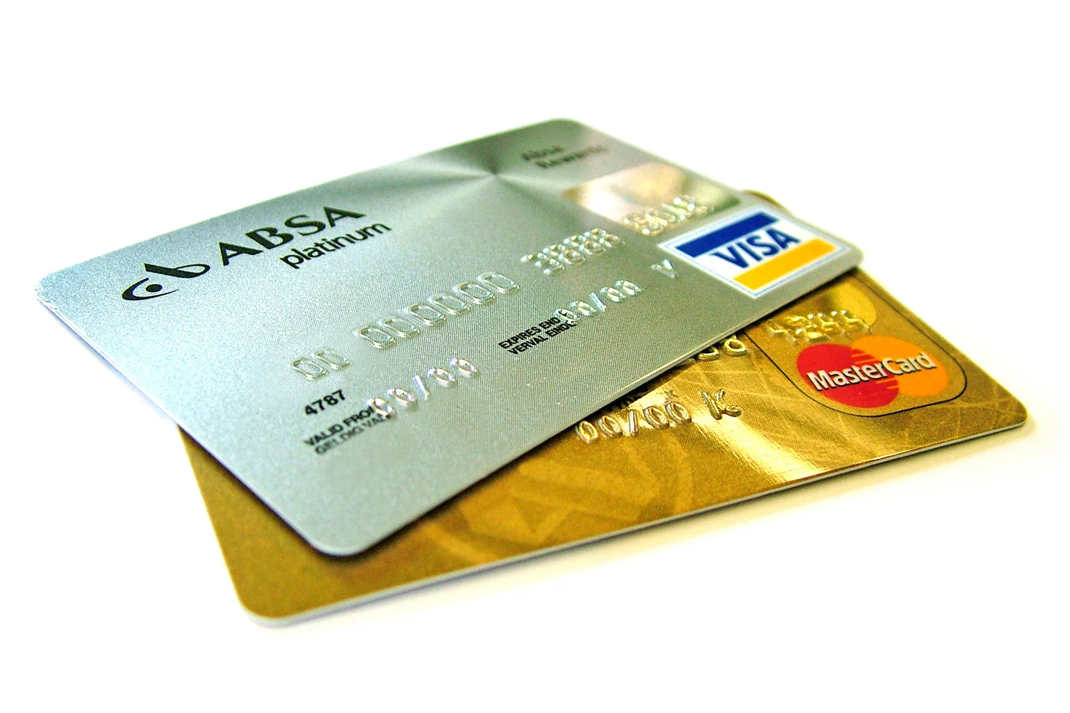 Two credit cards, a silver Visa and a gold MasterCard, lying on top of each other on a white surface.