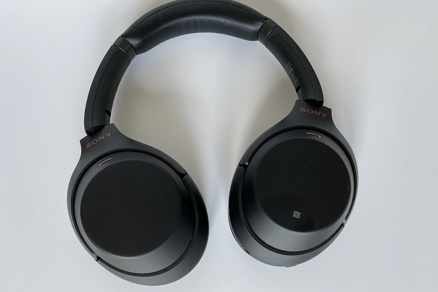A pair of black over-ear wireless noise-cancelling headphones lying on a light surface.