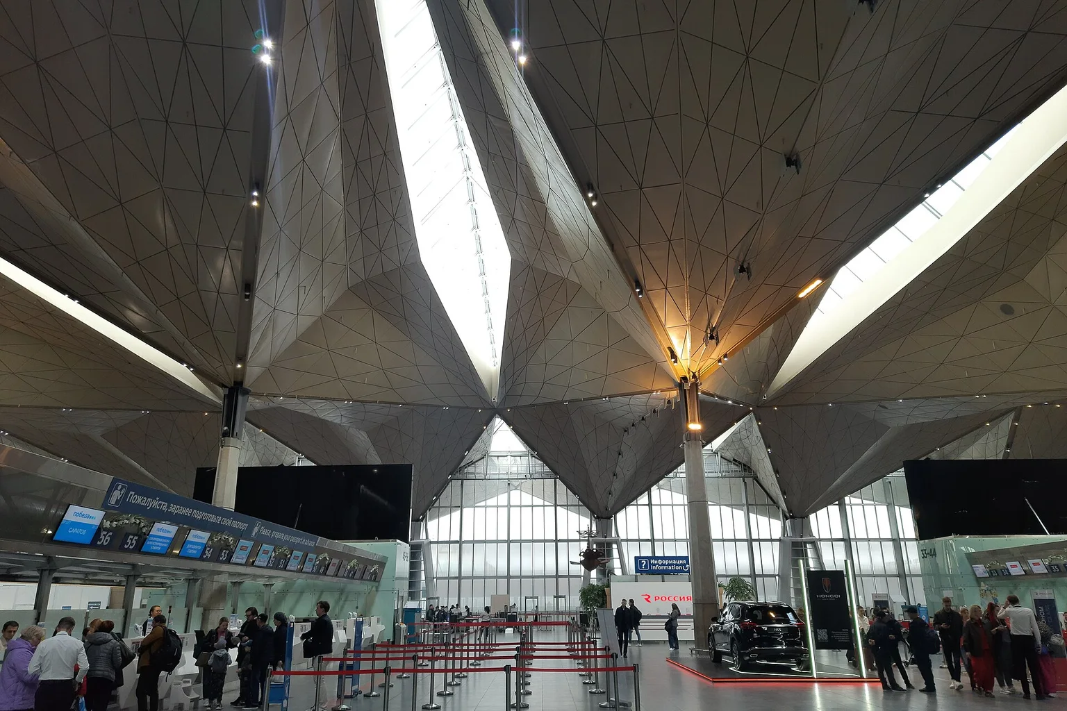 Interior of the Pulkovo Airport terminal in St. Petersburg, with a faceted ceiling, check-in counters and travelers