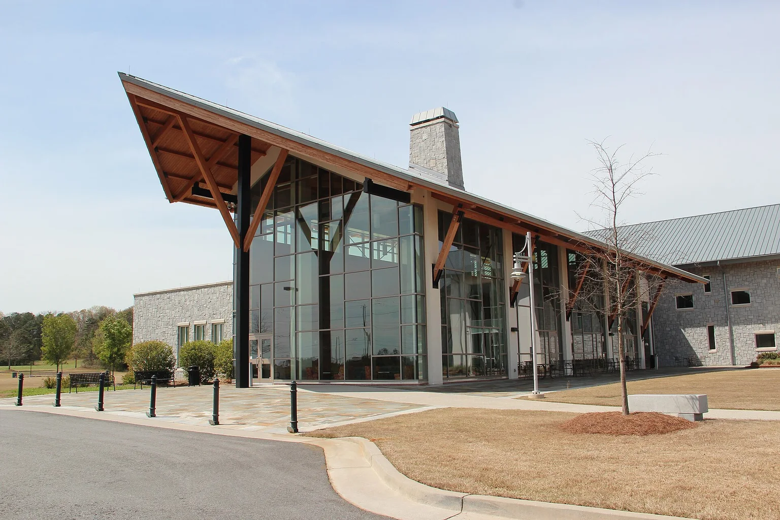 Modern glass-fronted building with a wooden-trussed roof on the Georgia Highlands College Cartersville campus, under a clear sky.