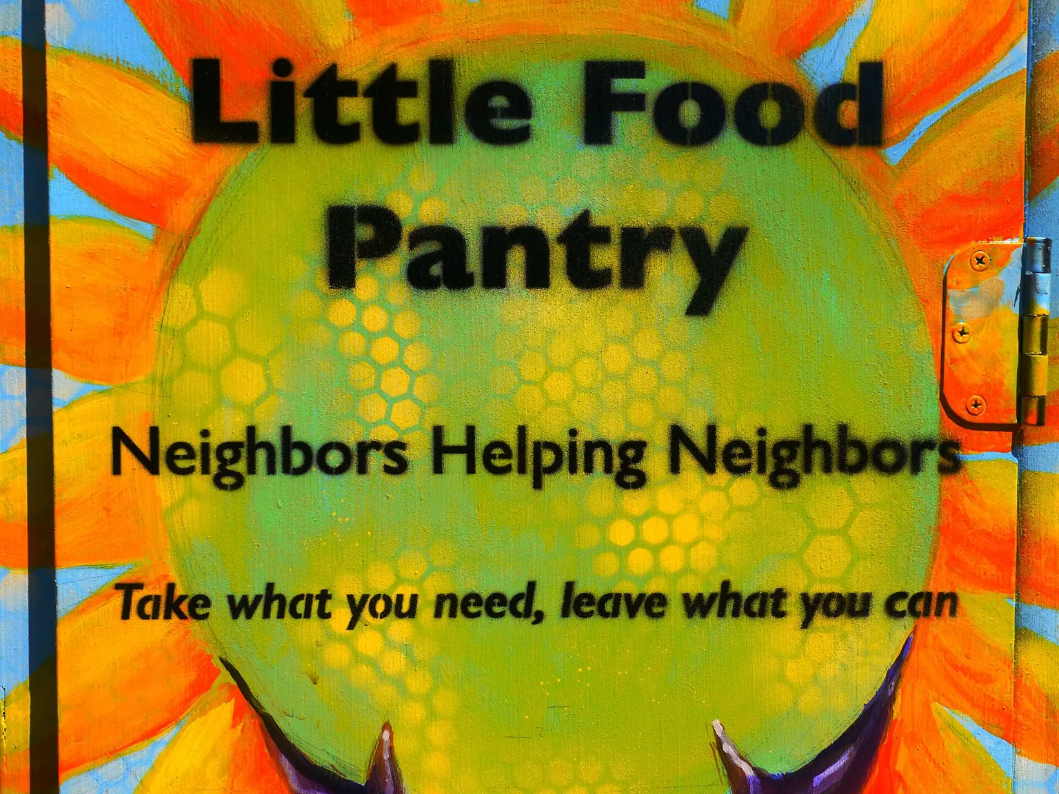 A brightly painted sign reading Little Food Pantry, Neighbors Helping Neighbors, Take what you need, leave what you can.